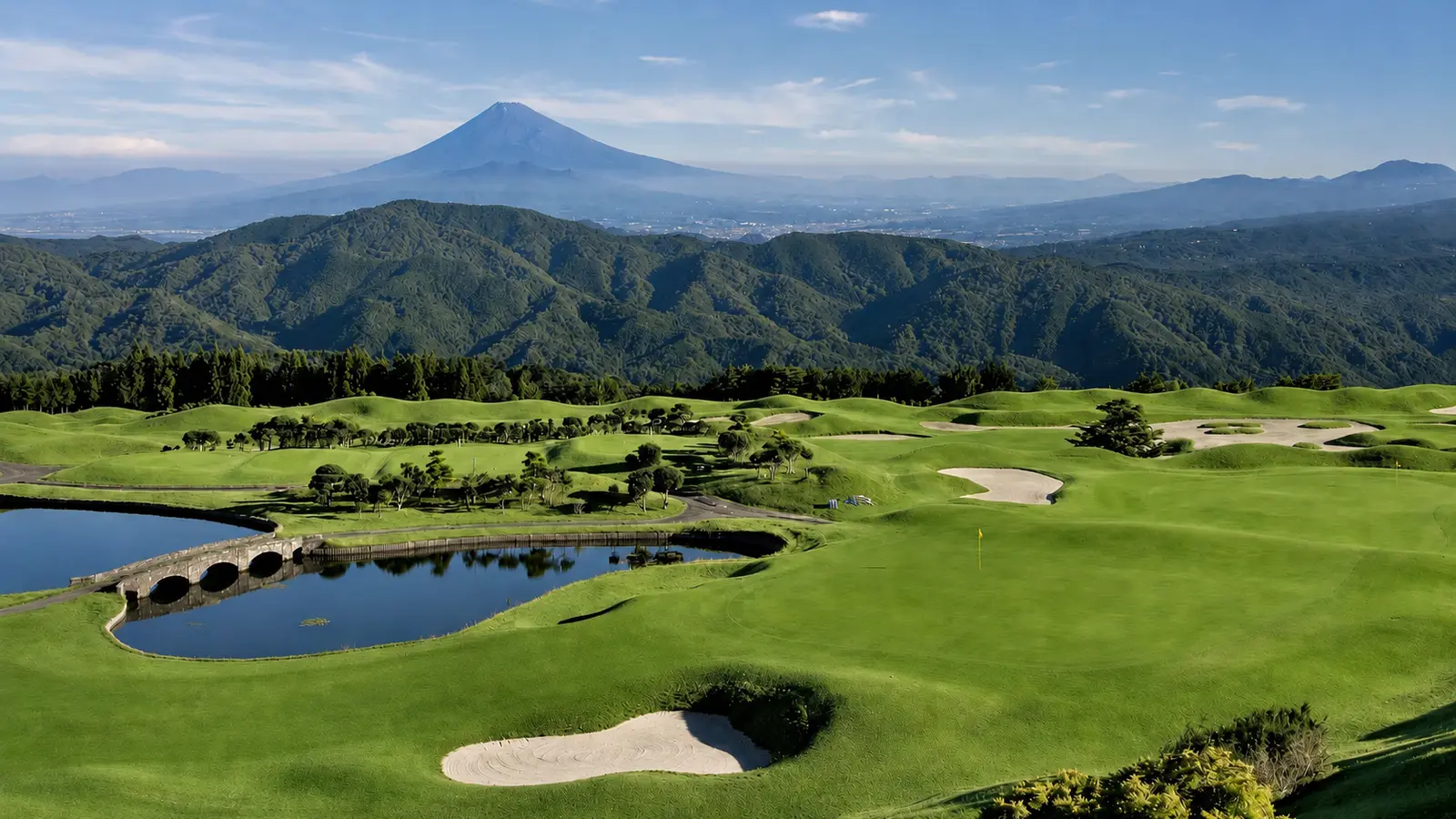 Mount Fuji beyond the fairways, bunkers, stone bridge and pond at Izu Heights Golf Club